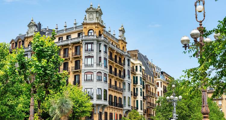 Elegante appartementsgebouwen uit de late 19de eeuw met balkons en een sierlijke klokkentoren in San Sebastian.