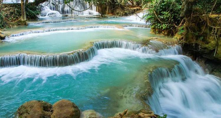 Turquoise getrapt zwembadjes en waterval van Kuang Si Falls omringd door weelderig jungle
