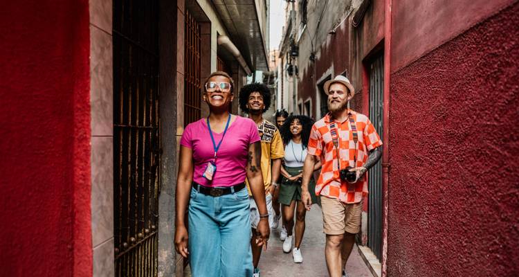 Grupo de turistas jóvenes caminando por un callejón estrecho y colorido en un tour urbano por las calles