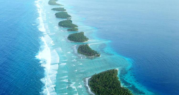 Spectaculaire luchtfoto van een ketting van smaragdgroene eilandjes omgeven door turquoise riefwateren.