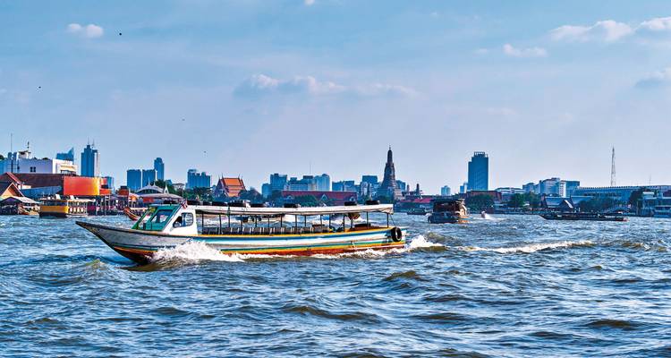 Longschwanzboot, das schnell den Chao Phraya Fluss entlangfährt, mit der Skyline von Bangkok im Hintergrund