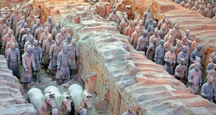Reihen von lebensgroßen Terrakotta-Krieger-Statuen und Pferden in ausgegrabenen Erdgruben.