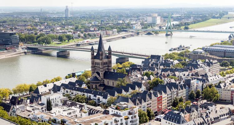 Panorama aérien de Cologne montrant la Grande Église Saint-Martin, le Rhin et les ponts par une journée brumeuse.