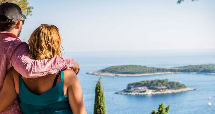Couple enlacé admirant de petites îles vertes de l'Adriatique depuis un point de vue en hauteur.