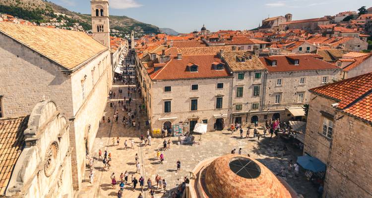 Vue aérienne des rues en calcaire de Dubrovnik et de ses toits en terre cuite animés de visiteurs à l'intérieur des murailles médiévales de la ville.