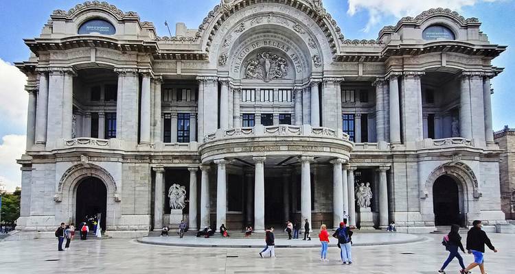 Großartige Fassade des Palacio de Bellas Artes in Mexiko-Stadt mit Besuchern, die über seinen Platz flanieren.
