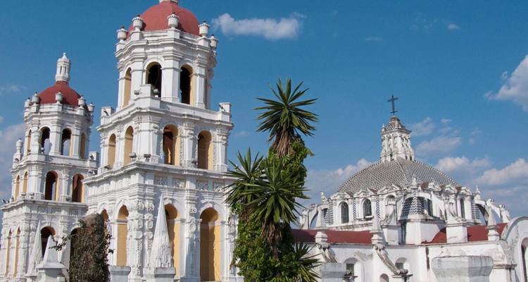 Historische weiße Kirchentürme und Kuppeln im Kolonialstil vor einem strahlend blauen Himmel von Puebla.