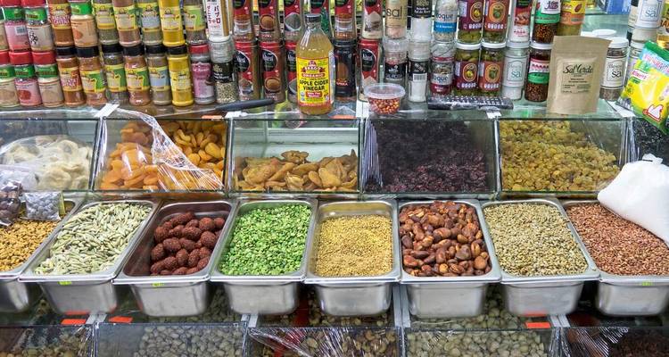 Farbenfroher Marktstand in der Halle mit Behältern voller Gewürze, getrockneter Früchte und abgefüllter Würzmittel.
