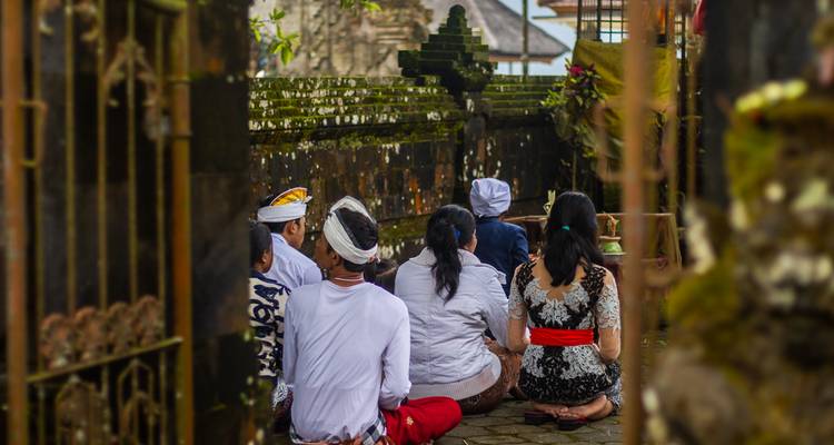 Des habitants s'agenouillent en prière dans une cour de temple balinais richement orné.