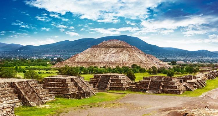 Breed uitzicht op de Piramide van de Zon en omliggende tempels in Teotihuacán onder een dramatische hemel.