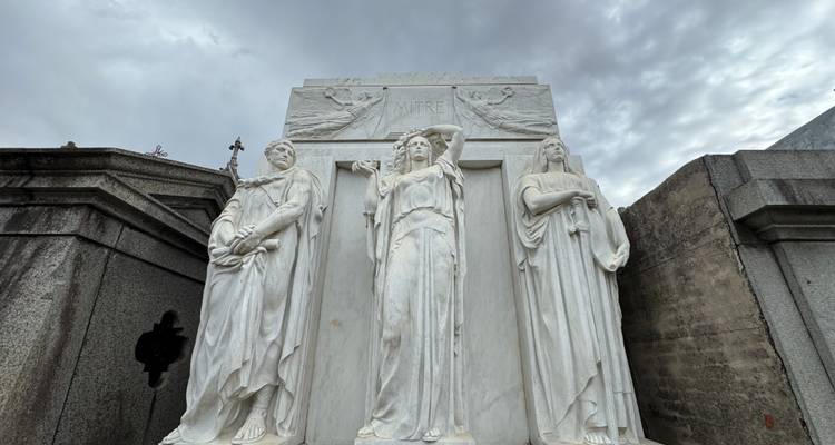 Witte marmeren grafbeelden op de Recoleta-begraafplaats tegen een sombere grijze lucht.
