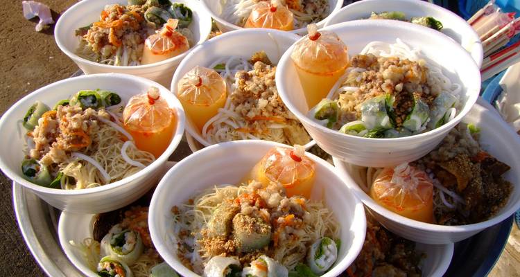 Close-up display of Cambodian street food bowls filled with noodles, meat and vegetables.