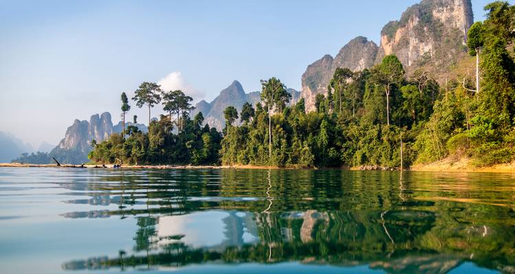 Le lac aux eaux cristallines reflète des montagnes calcaires aux pics déchiquetés et une rive de jungle luxuriante.