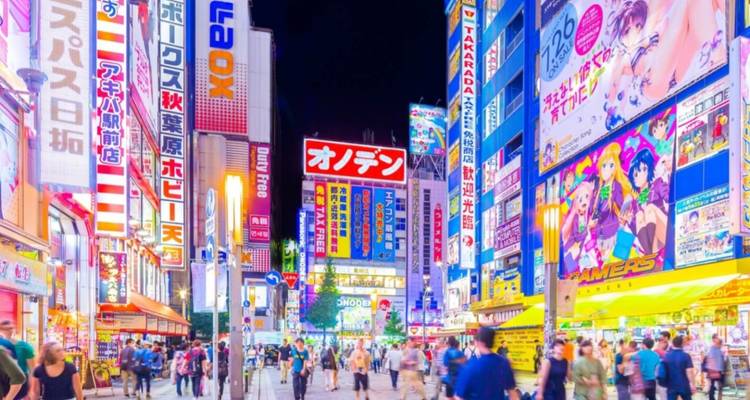 Eine lebendige Nachtszene in Akihabara mit leuchtenden Neonzeichen und Menschenmengen, die durch die Straße flanieren.