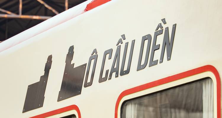 Nahaufnahme von vietnamesischen Schriftzeichen, die auf der Seite eines cremefarbenen Zugwagens angebracht sind.