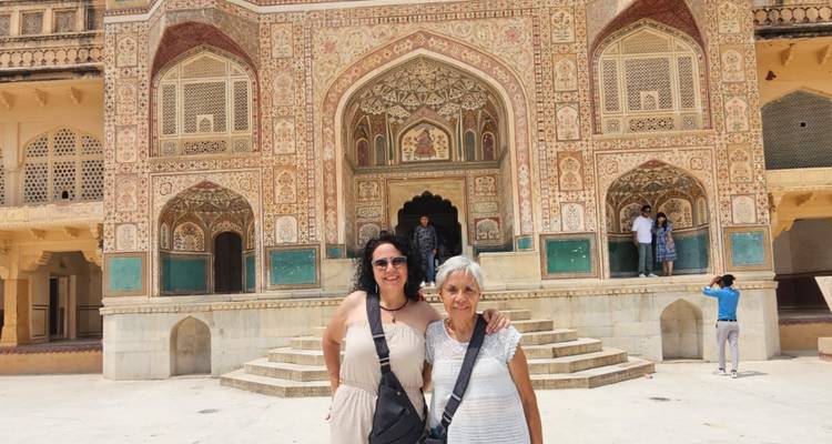 Deux touristes sourient devant la porte Ganesh Pol, magnifiquement décorée, du fort d'Amber.