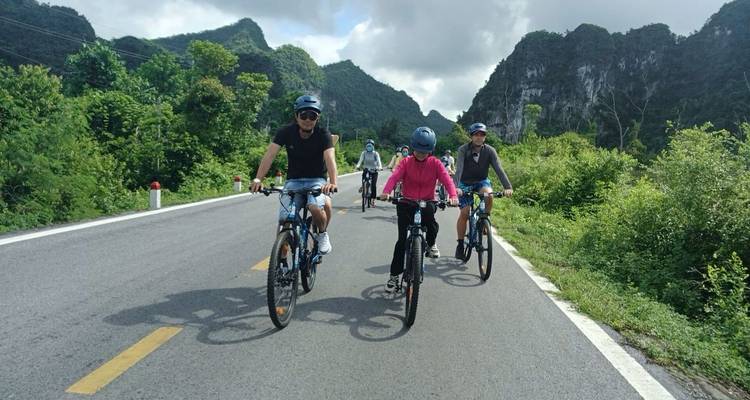 Los ciclistas pedalean por una carretera tranquila rodeada de acantilados de piedra caliza exuberantes y vegetación verde.