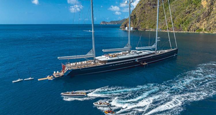 Yacht de luxe à plusieurs mâts ancré dans les eaux cristallines des Caraïbes avec des annexes en circulation.