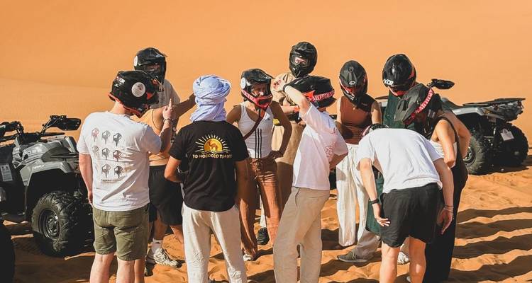 Groep in helmen verzameld naast quad bikes, klaar voor een woestijnrit