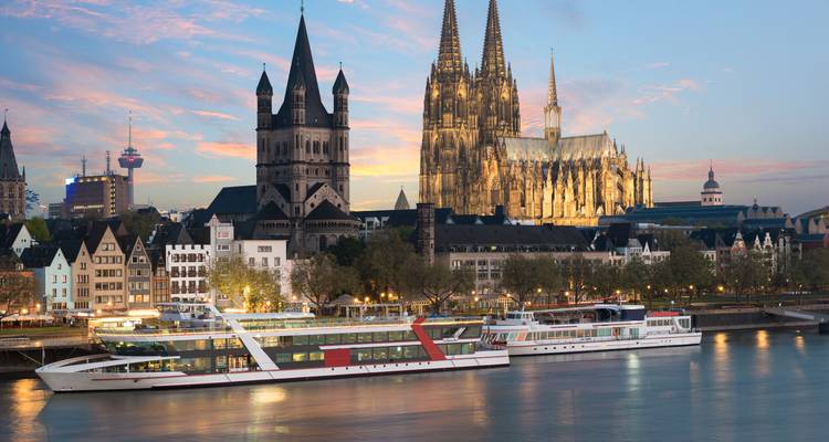 Vue en soirée de la Cathédrale de Cologne et des bateaux du Rhin au coucher du soleil.