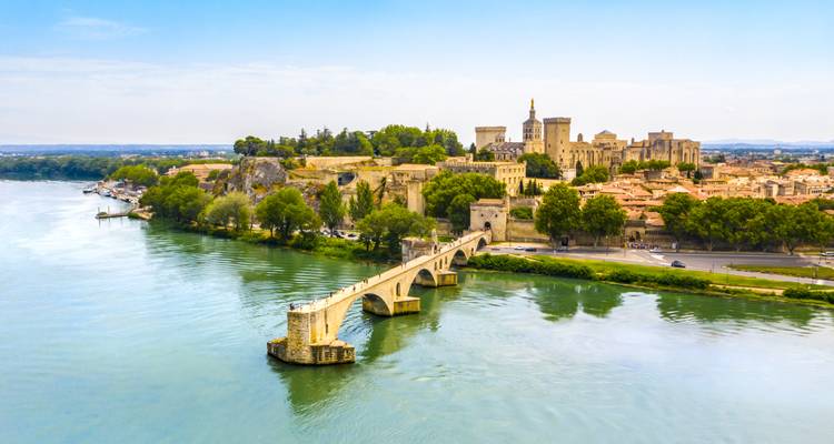 Aerial perspective of the historic bridge of Avignon leading toward the Pope’s Palace beside the Rhône River.