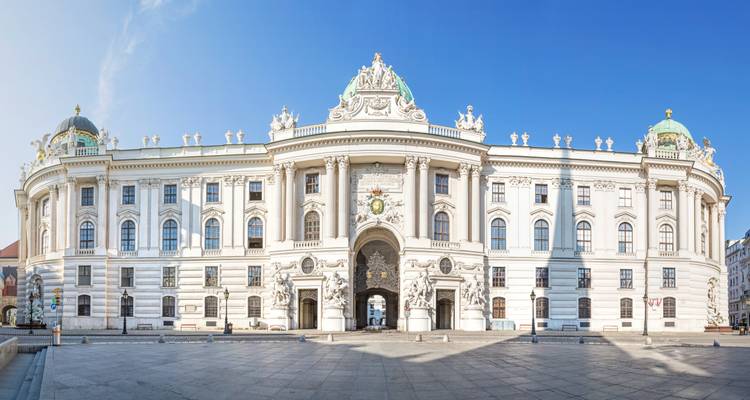La façade baroque blanche grandiose du Palais de la Hofburg de Vienne (Michaelertrakt) s'élève sous un ciel bleu dégagé.