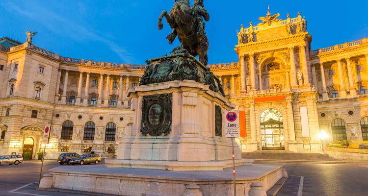 Verlichte ruitersstandbeeld van prins Eugen voor het indrukwekkende Hofburg-paleis in Wenen tijdens het blauwe uur.