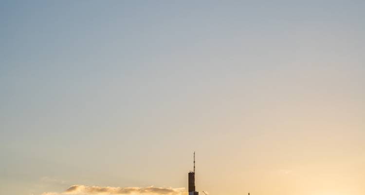 Minimalistische skyline-uitzicht op de silhouet van Frankfurts Commerzbank Tower bij zonsopgang met pastelkleurige lucht en een vleugje wolken.