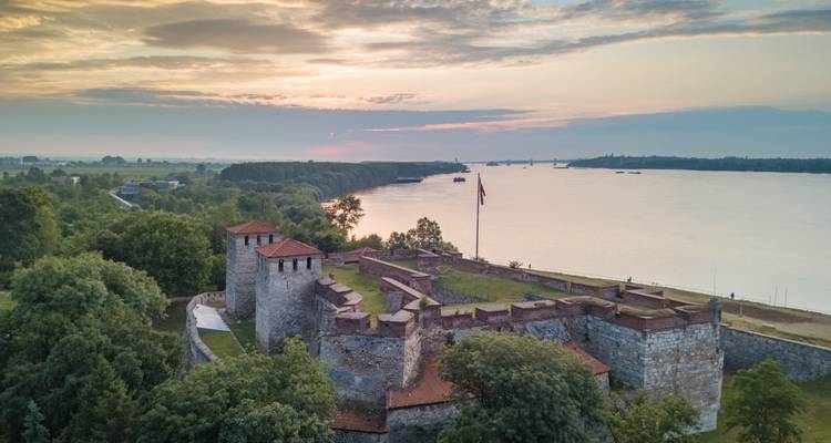 Vue aérienne par drone de la forteresse médiévale Baba Vida sur le Danube au coucher du soleil avec un horizon fluvial brumeux.
