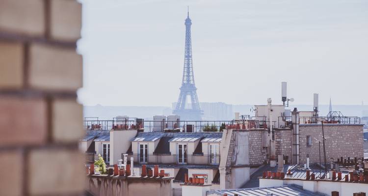 La Tour Eiffel se dressant au loin au-dessus des toits parisiens classiques par une matinée voilée
