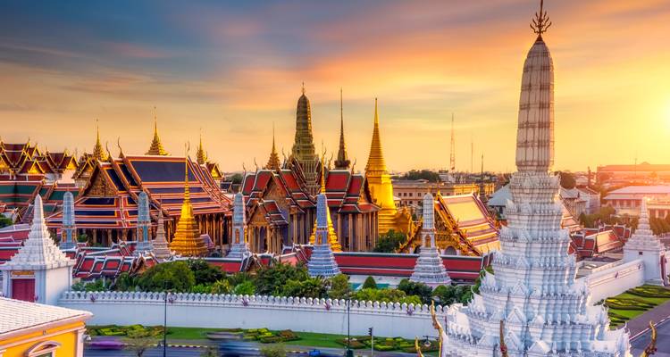 Golden evening light over Bangkok’s Grand Palace complex with gleaming stupas and temples