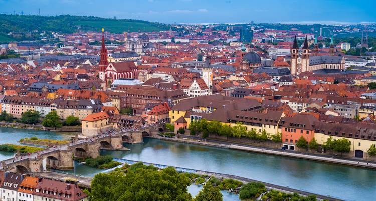 Panoramisch uitzicht over Würzburg met de Alte Mainbrücke die over de rivier spangt en de roodgedekte oude stad die zich daarachter uitstrekt.