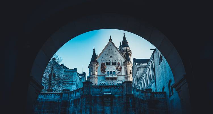 Vue à travers une arche sombre encadrant les tourelles de conte de fées du château de Neuschwanstein