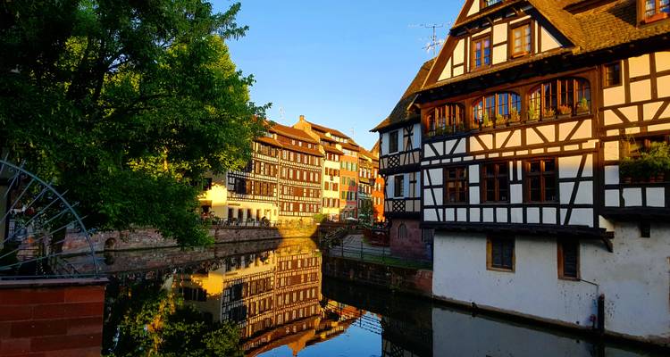 La lumière du matin illumine les maisons à colombages qui se reflètent dans un étroit canal du quartier de la Petite France à Strasbourg.
