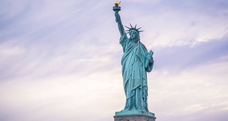 Iconic Statue of Liberty standing tall against a pastel sky.