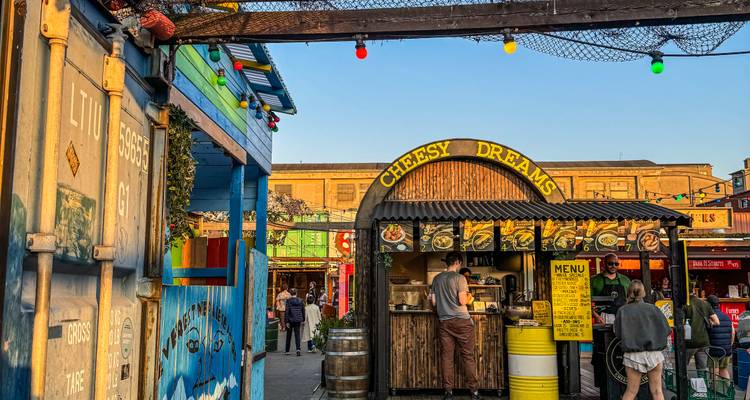 Kleurrijke straatvoedselkraam genaamd Cheesy Dreams waar klanten snacks bestellen op een containermarkt.