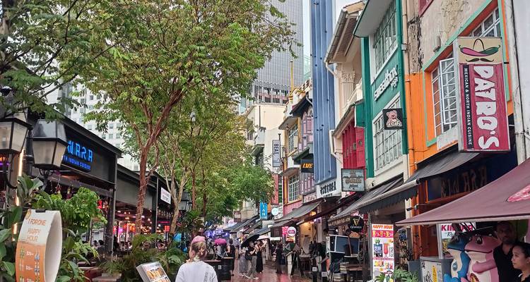 Lebendige Fußgängerzone mit farbenfrohen Shophouses, Restaurants und Regenschirmen nach einem Regenschauer