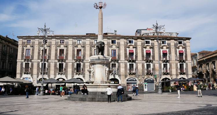 Spacieuse piazza à Catania avec le célèbre obélisque de la Fontaine de l'Éléphant, les bâtiments baroques environnants et les visiteurs.