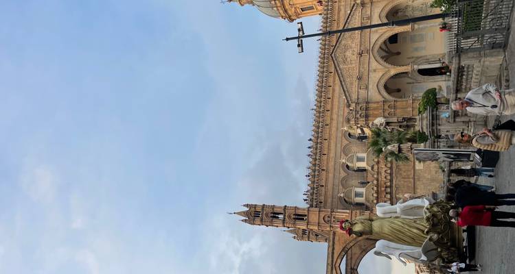 Cathédrale gothique de Palerme avec ses arcs ornementés, ses statues et des personnes rassemblées sur la place lors d'un événement en plein air.