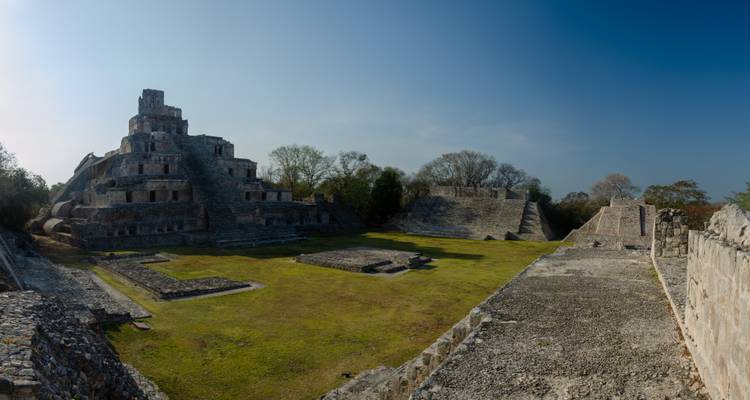 Panoramisch uitzicht op een meerlagige ronde Maya-piramide en omringende pleinen onder een heldere blauwe lucht