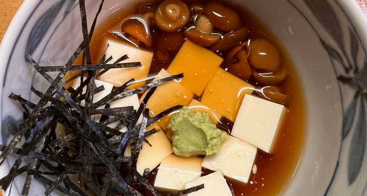 Klein schaaltje met tofu blokjes, champignons en bouillon, afgewerkt met wasabi en nori stroken.