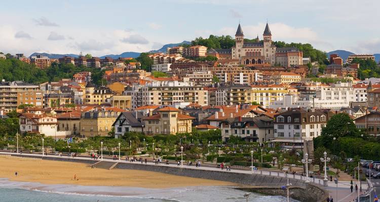 Paisaje urbano frente al mar de San Sebastián con torres históricas y bahía de arena en forma de media luna