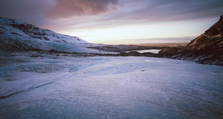 Vaste paysage glaciaire sous un ciel vespéral coloré.