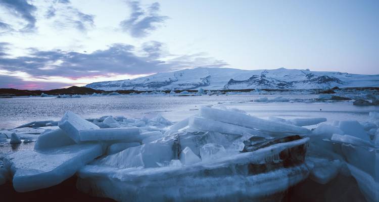 Les icebergs dérivant sur un lagon calme avec des pics enneigés au crépuscule.