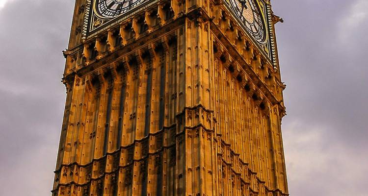 Gros plan du cadran d'horloge orné et de la maçonnerie dorée du Big Ben sur un ciel gris morose.
