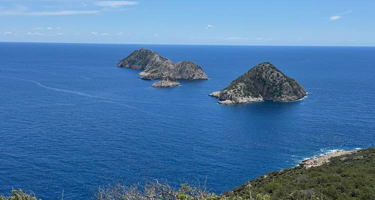Trois petits îlots rocheux dans une mer d'un bleu éclatant sous un ciel dégagé