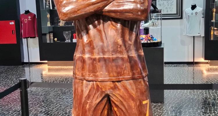 Een houten beeld van een voetballer met gevouwen armen in het CR7 Museum.
