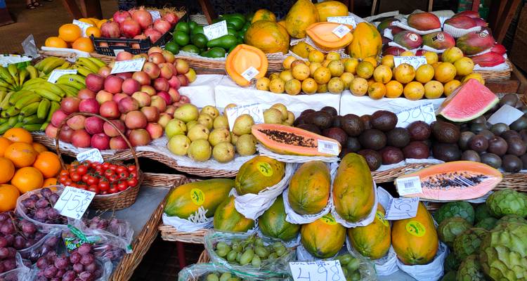 Een levendige fruitkraam op Mercado dos Lavradores met exotische producten netjes uitgestald met prijskaartjes.
