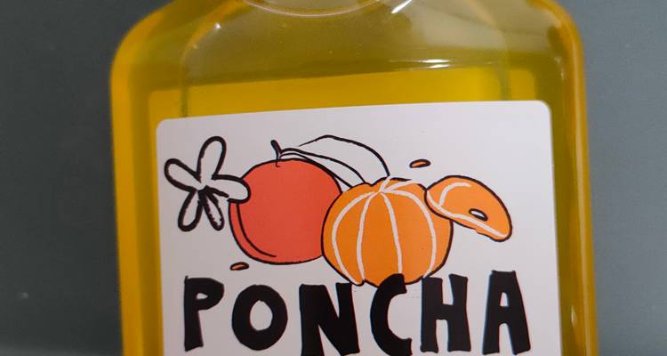 Primer plano de una pequeña botella de licor Poncha con una ilustración colorida de frutas.