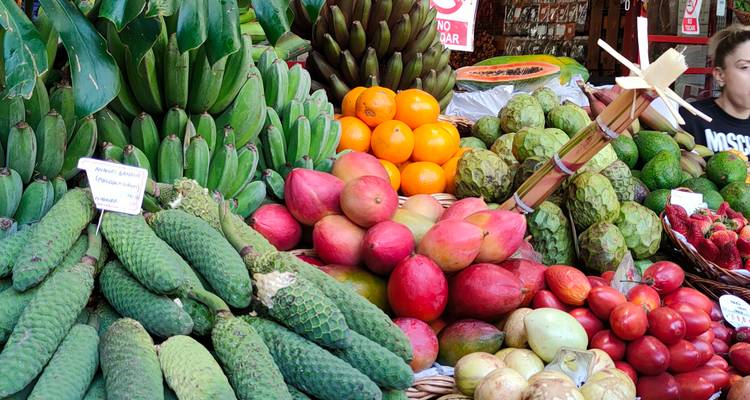Colorida exhibición de frutas en un puesto de mercado concurrido con productos tropicales de Madeira.